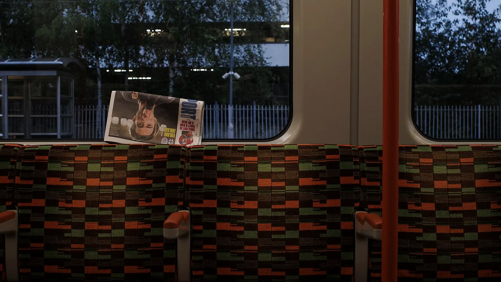 An empty metro carriage with a forgotten newspaper on the seat