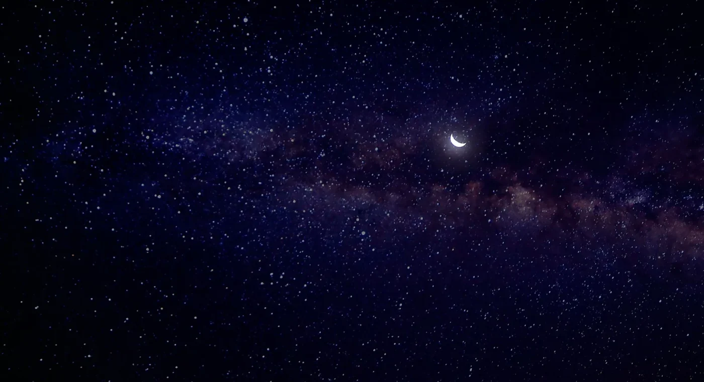 A small crescent moon glowing among countless stars at night